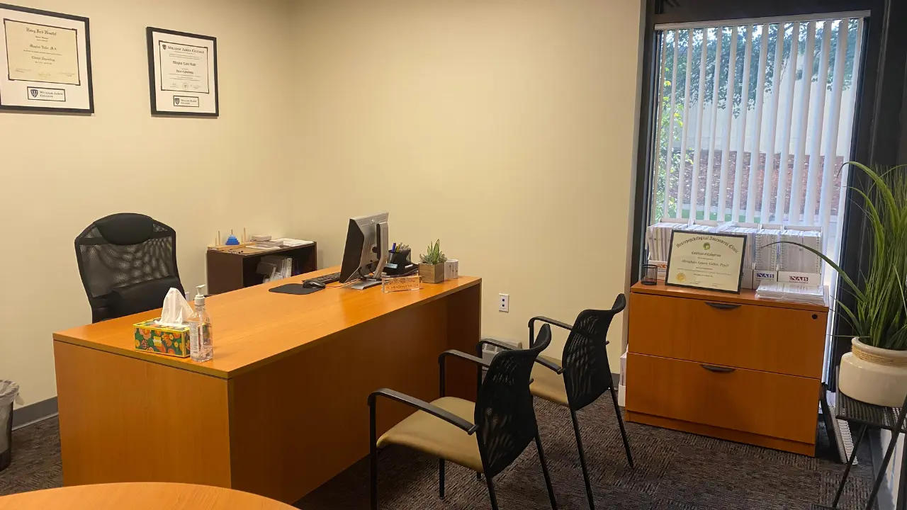 A Boston Neurobehavioral Associates clinic in Massachusetts with a desk, chairs, and framed certificates. BNBA